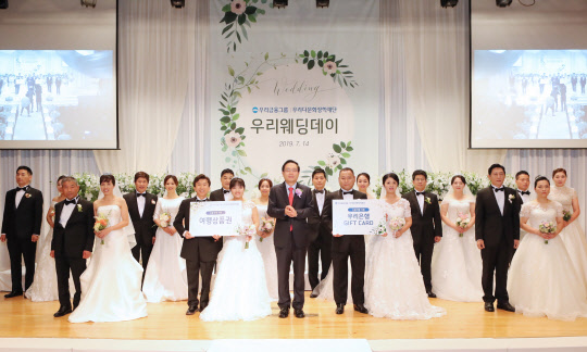 우리금융그룹이 지난 14일 서울 소공로 우리은행 본점 비전홀에서 다문화 부부를 위한 합동결혼식인 '제8회 우리웨딩데이'를 개최한 가운데 손태승 우리다문화장학재단 이사장(가운데)이 10쌍의 다문화 부부와 기념촬영을 하고 있다. 우리금융그룹 제공